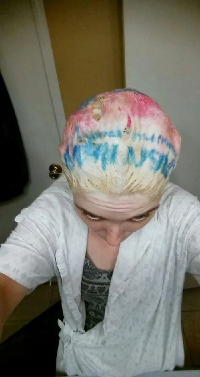 A person with patchy pink and blue dyed hair looking down depicting beauty procedures fails.