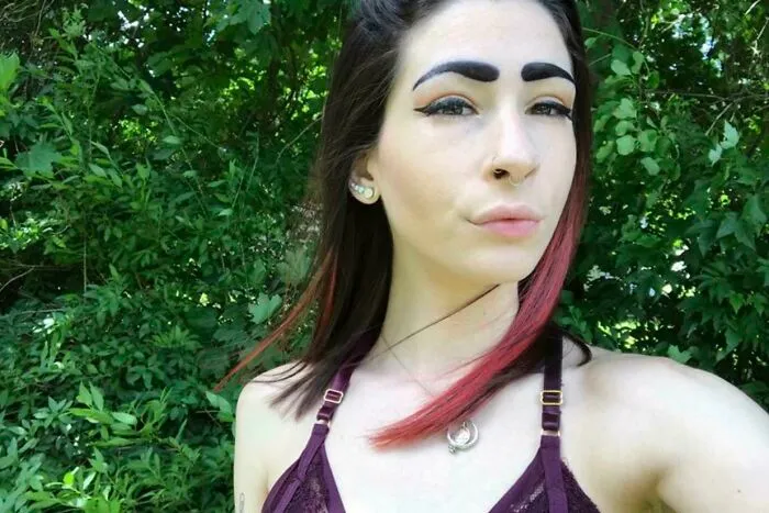 A close-up of a young woman with poorly shaped, thick blocky eyebrows showing beauty procedures fails.