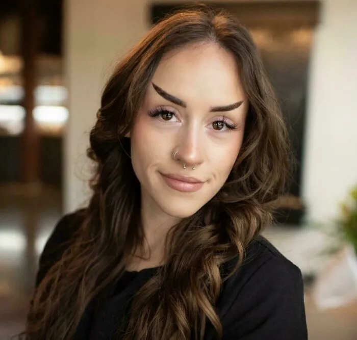 A young woman with oddly shaped, sharply angled eyebrows, demonstrating quirky beauty procedures fails.