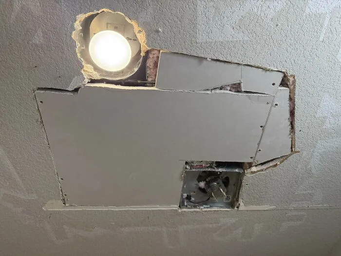 Ceiling repair with uneven drywall and exposed light fixture showing questionable DIY projects
