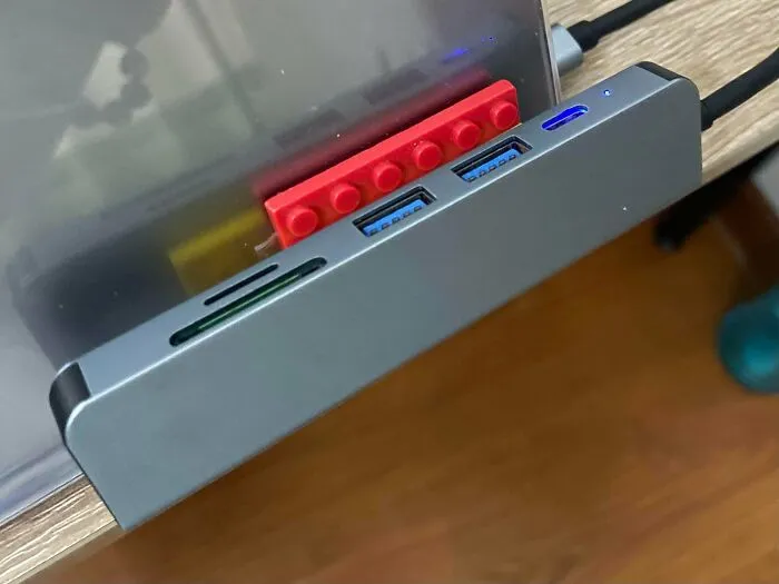Computer USB hub wedged into place using a red toy brick for questionable DIY projects