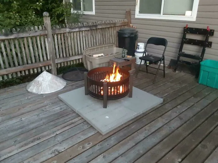 A fire pit placed on stone tiles on a wooden deck as part of questionable DIY projects.