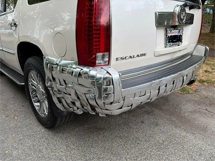 Rear bumper of a white SUV repaired with woven metal straps as one of many questionable DIY projects.