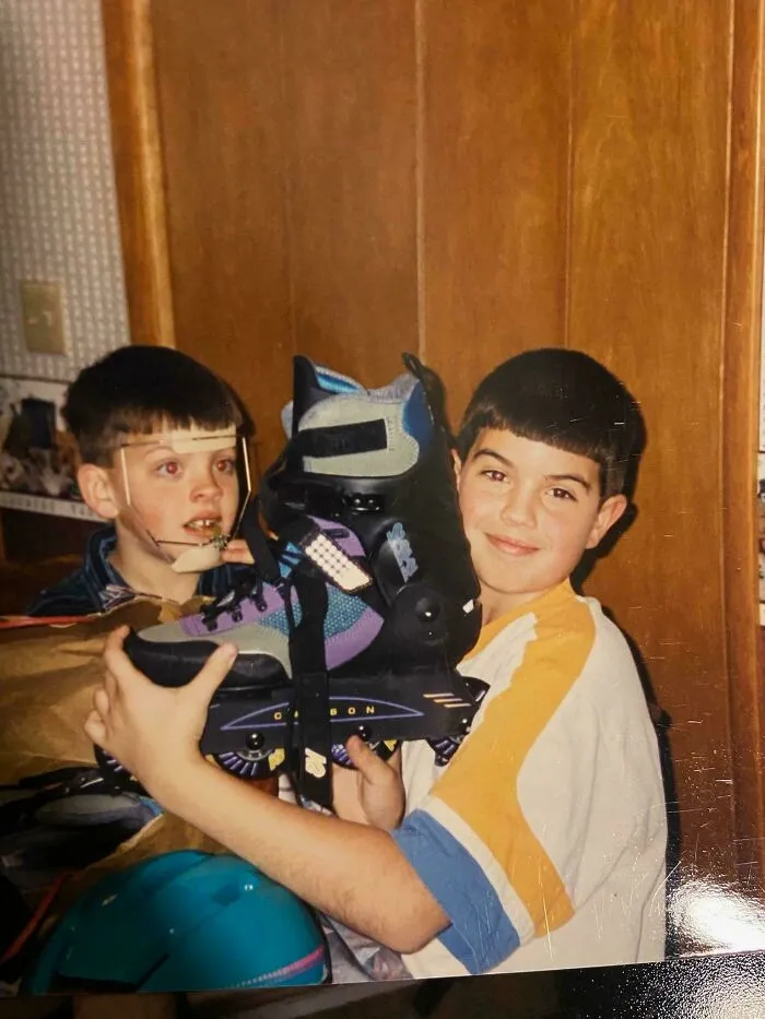 Two boys from the 90s, one with orthodontic headgear, holding a rollerblade in a post about the 90s.