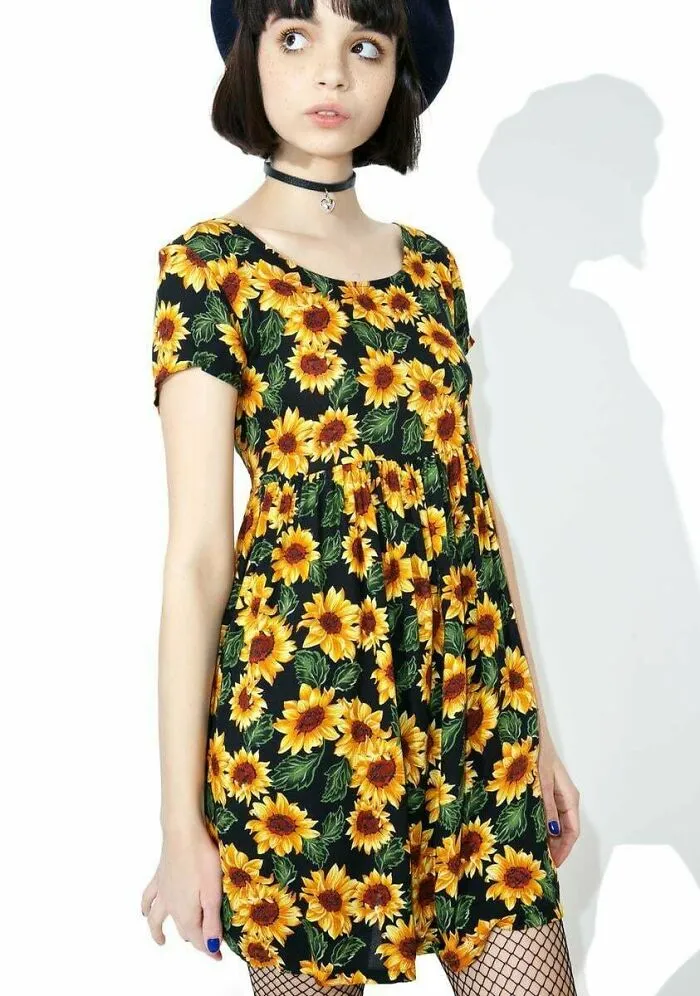 A young woman modeling a classic 1990s style sunflower print dress with a black choker necklace