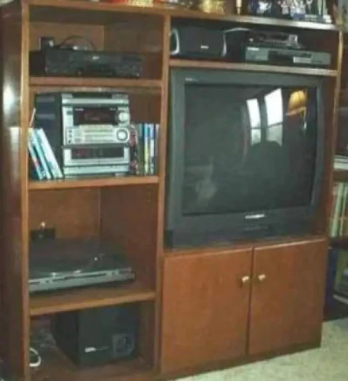 A classic 90s wooden entertainment center holding a CRT television and a stereo system to remember the era
