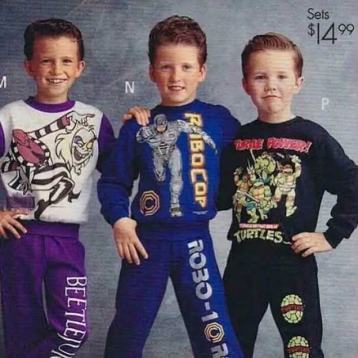 Three young boys posing in 90s themed graphic sweatpants and sweatshirts featuring Beetlejuice, Robocop, and TMNT.