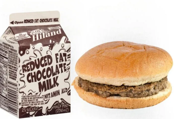 A carton of Hiland reduced fat chocolate milk next to a school cafeteria hamburger, showcasing 90s nostalgia.