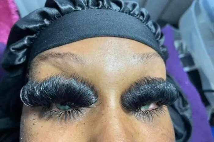 A woman wearing excessively thick, heavy eyelash extensions, representing clear beauty procedures fails.