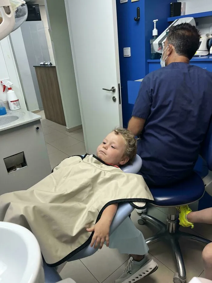 A toddler reclining in a dental chair during an appointment, showcasing wholesome pics of dads supporting kids