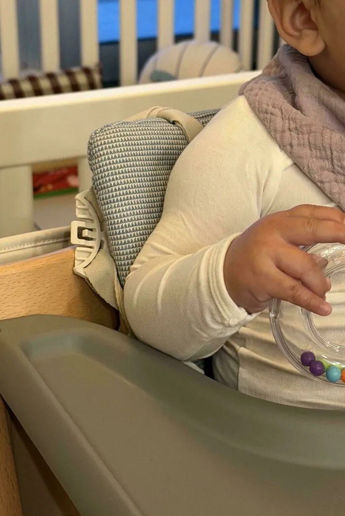 A close up of a baby holding a toy in a high chair, featured in wholesome pics of dads sharing sweet moments.