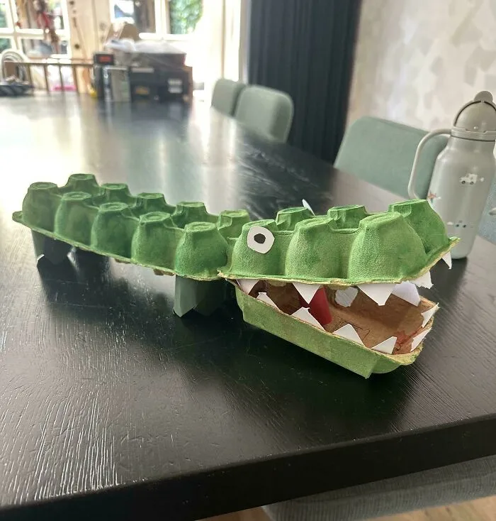 A handmade green crocodile craft made from an egg carton, featured in wholesome pics of dads creative activities