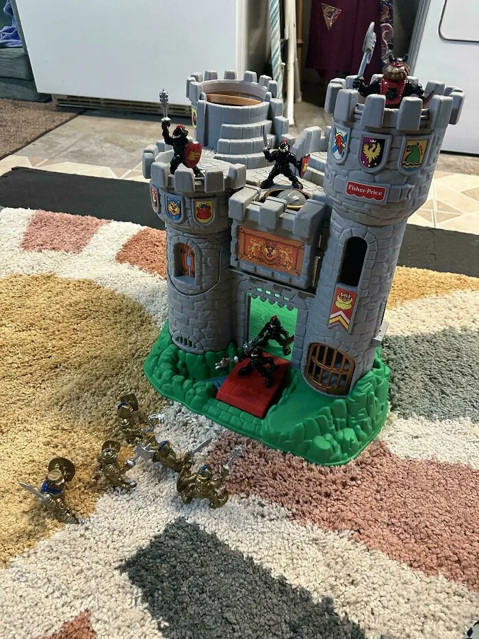 A toy castle setup on a rug with knight action figures, showcasing wholesome pics of dads sharing fun games with kids