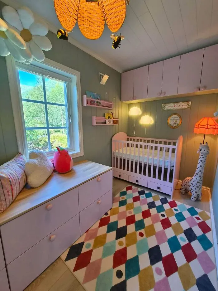A cozy and colorful nursery decorated by dads nailing fatherhood with a pink crib, dresser, and harlequin rug.
