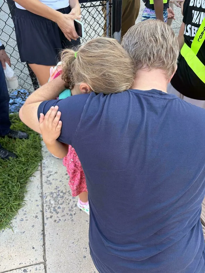 A wholesome moment of a dad comforting his young daughter with a warm hug