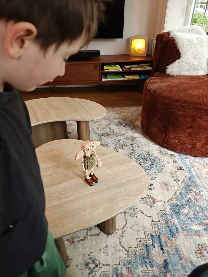A child looking at a toy figure on a table showcasing wholesome fatherhood and parenting moments