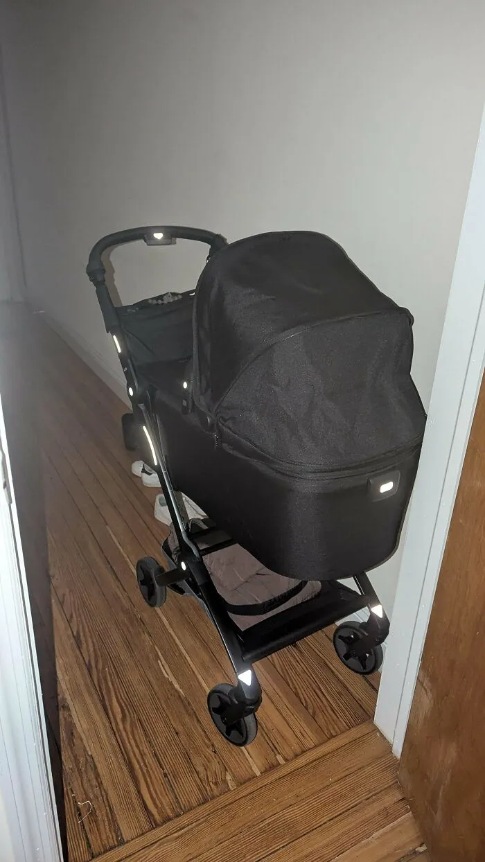 A modern black stroller parked in a hallway, representing wholesome pics of dads preparing for walks.