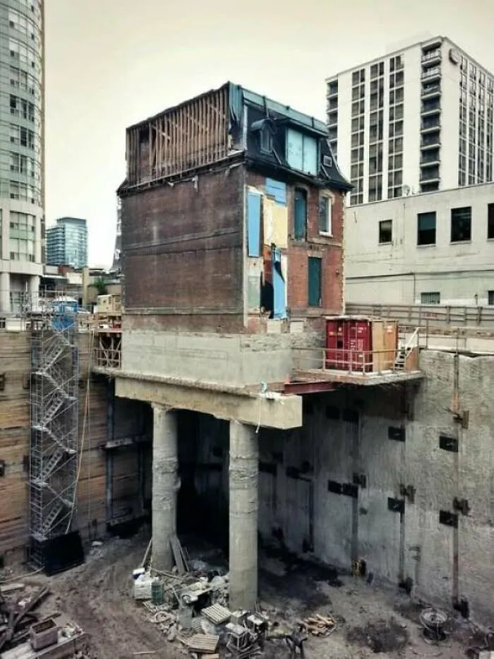 A small historical building preserved on concrete stilts during excavation, a curious architectural masterpiece.