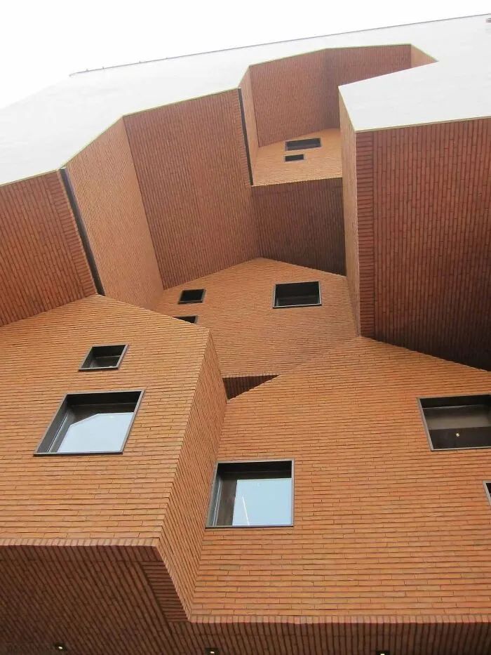 Angled facade of a contemporary brick building highlighted among architectural masterpieces.