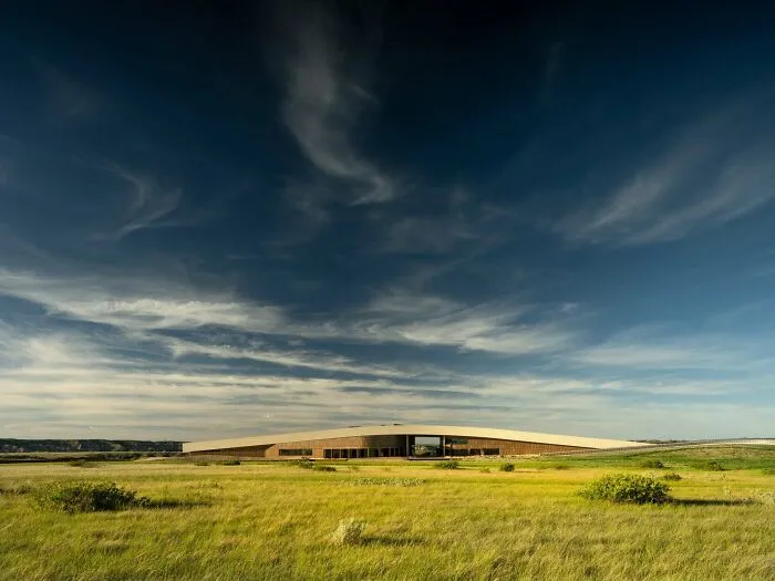 Modern low-rise building set in a wide grassy field representing architectural masterpieces.