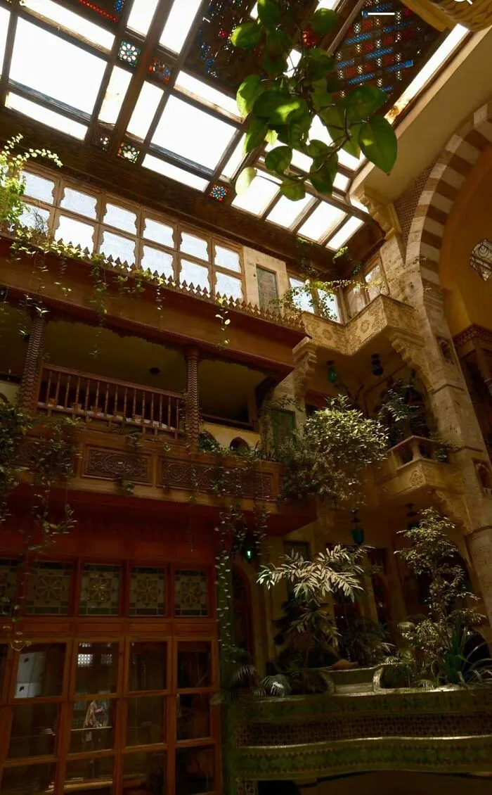 Interior courtyard with lush greenery and skylight showcasing architectural masterpieces.