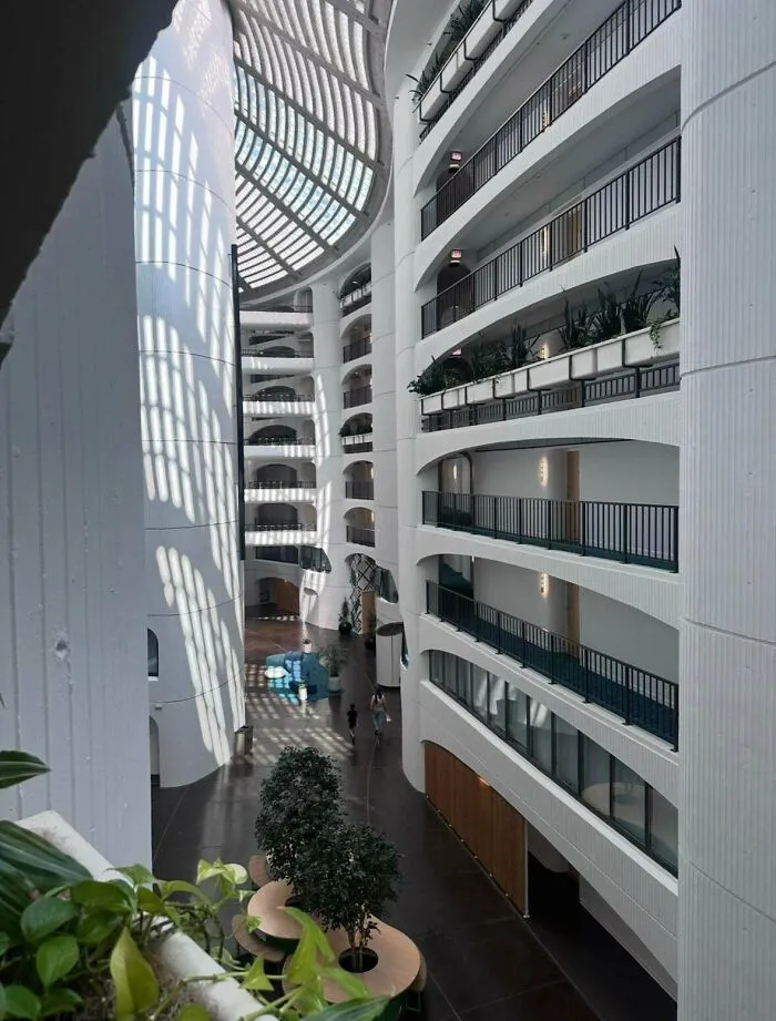 Interior view of a modern atrium with curved white balconies, showcasing a bright architectural masterpiece.
