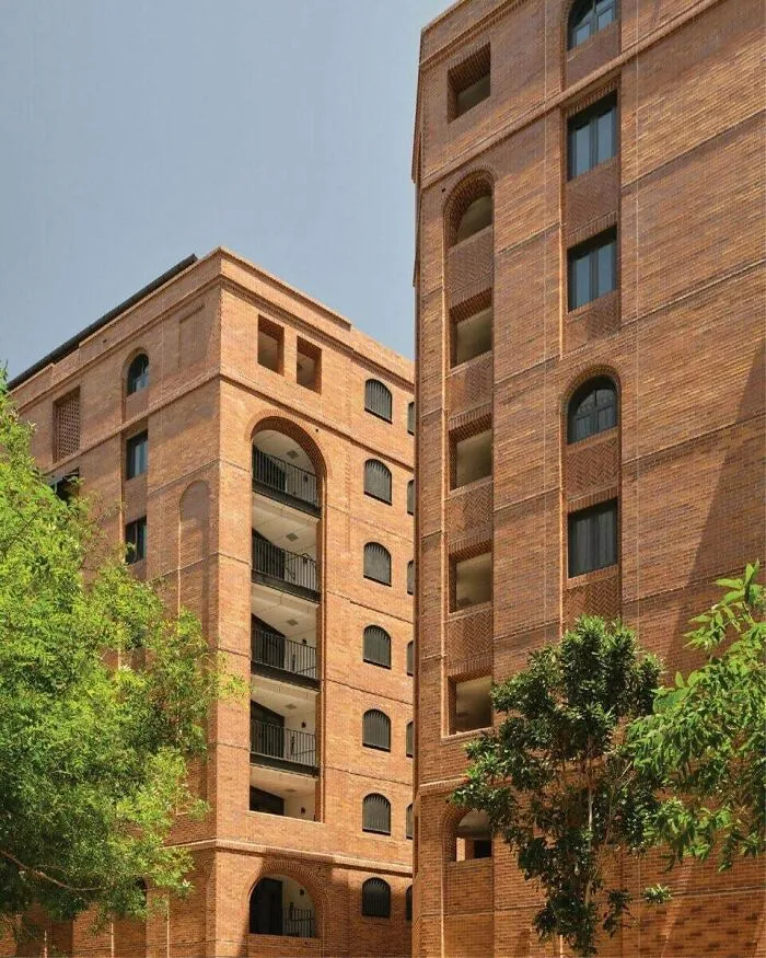 Detailed brick apartment buildings showcasing modern architectural masterpieces surrounded by green trees.