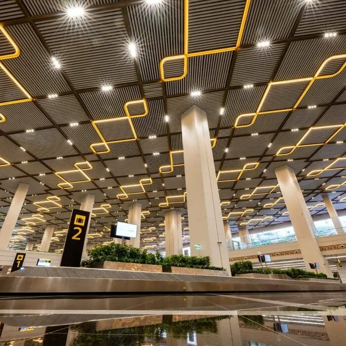 Modern airport interior with a geometric illuminated ceiling design, highlighted as architectural masterpieces.