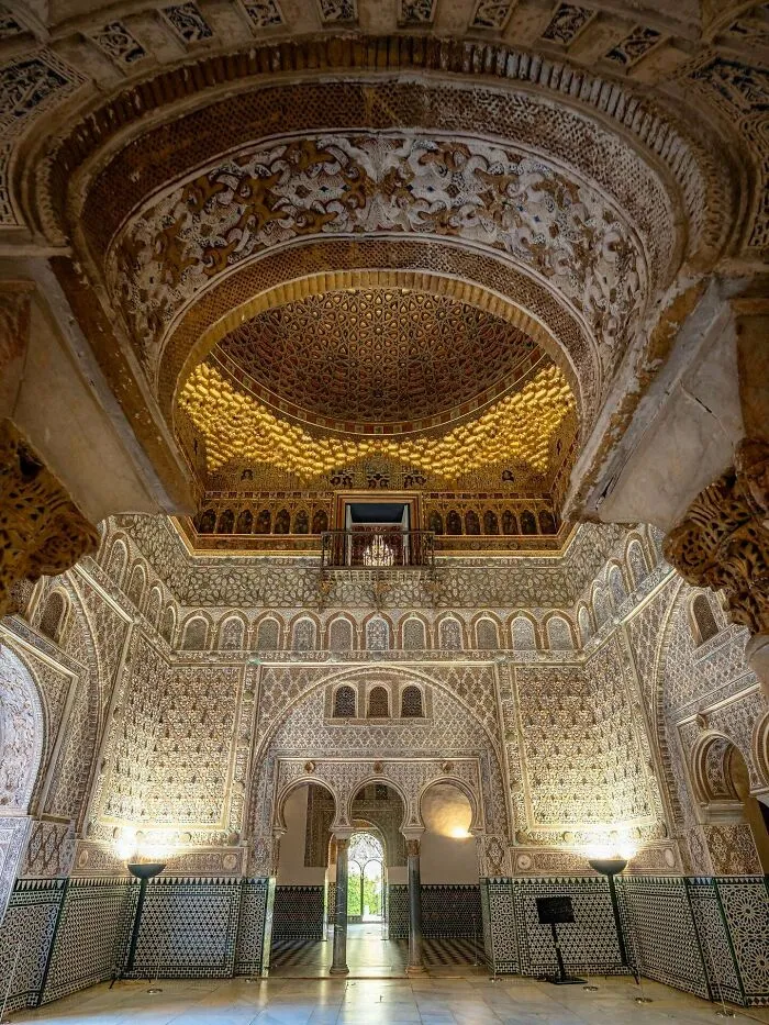 Intricately carved interior hall with ornate arches and a golden dome, representing historic architectural masterpieces.