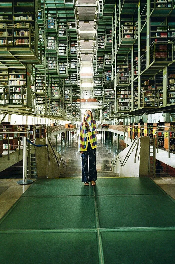 Person standing inside a futuristic multi-level library showcasing stunning architectural masterpieces.
