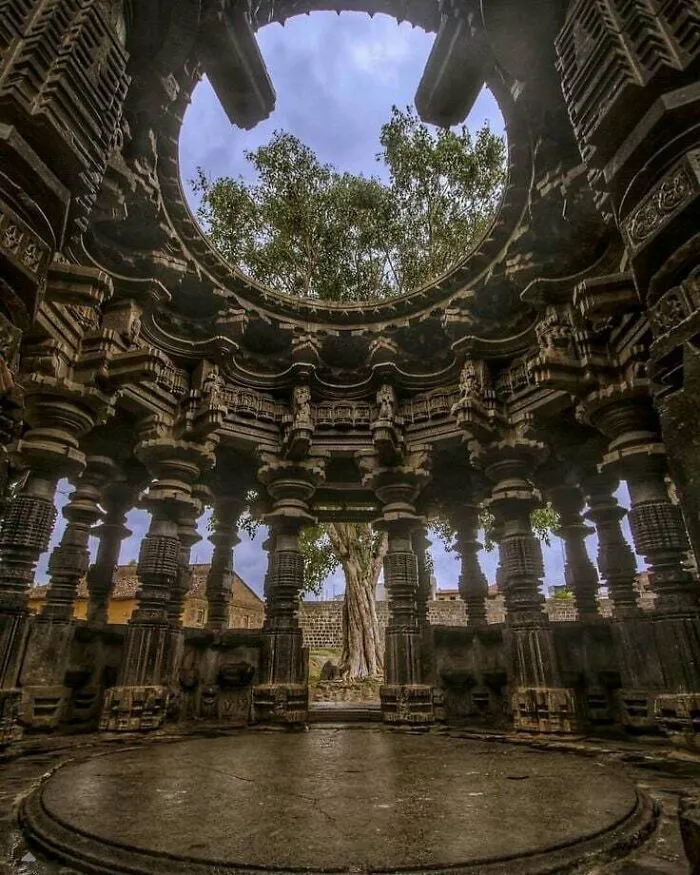 Intricately carved stone temple columns forming an architectural masterpiece with open circular ceiling.