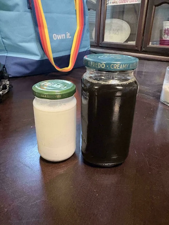 Two reused glass jars filled with liquids sitting on a wooden table for practical frugal tips.