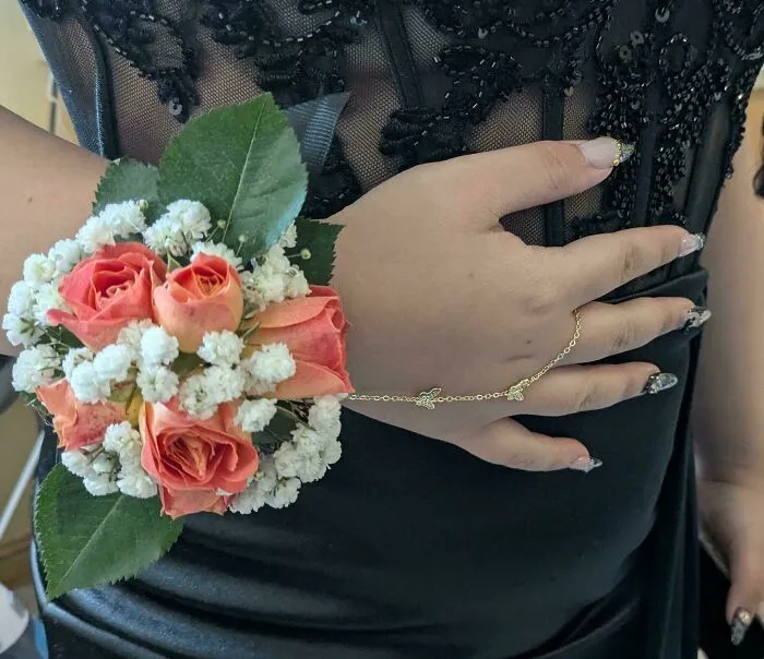 Floral wrist corsage on a person wearing a black dress representing smart frugal tips for saving money on events.