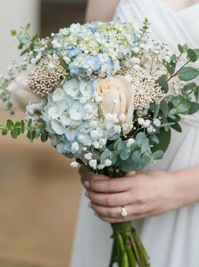 A bride holding a bouquet of flowers showcasing frugal tips for saving money on wedding arrangements.