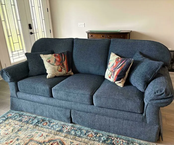 A dark blue sofa adorned with dog-themed throw pillows, representing comfortable frugal tips living.