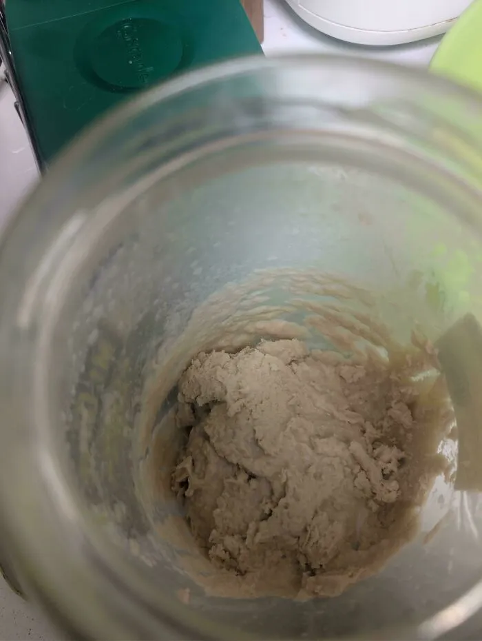 Close-up view of sourdough starter mixing inside a glass jar, demonstrating practical frugal tips for baking at home.