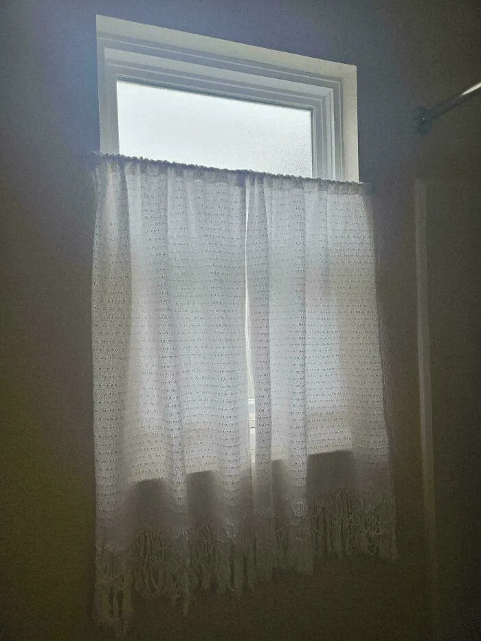 Simple white fringe curtain over a small window as one of many frugal tips.