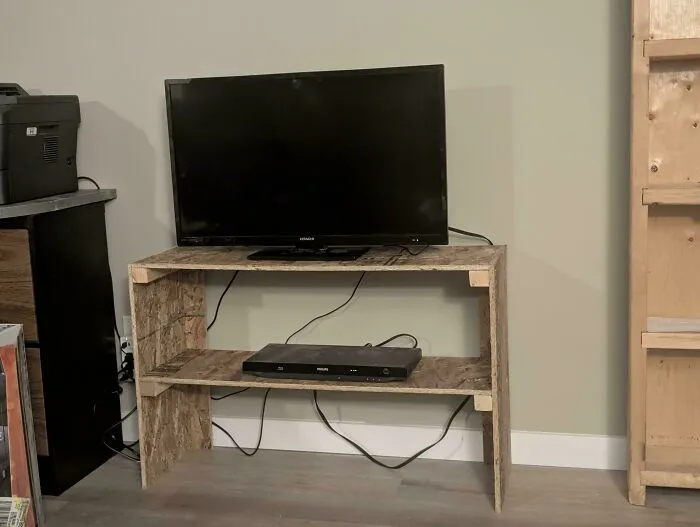 A homemade particle board TV stand displaying frugal tips for budget media setups.