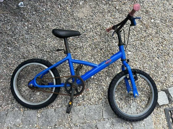 A blue bicycle resting on gravel, illustrating frugal tips for saving money on transport