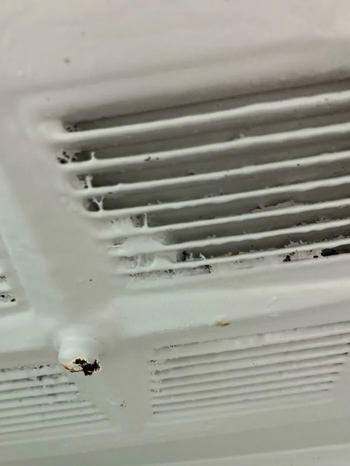 Close-up of a dirty ventilation grate with mold and dust, showing terrible landlords' lack of maintenance