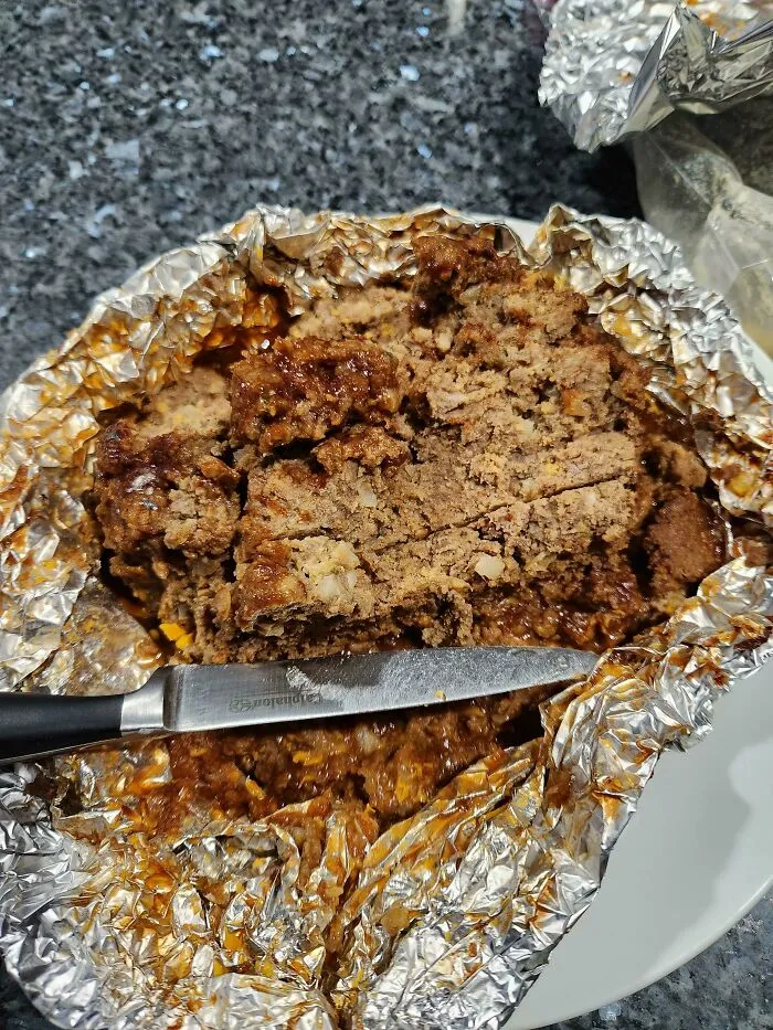 Homemade meatloaf in foil cut with a knife highlighting sheer audacity