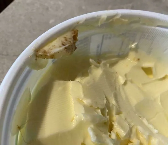 A tub of butter with toast crumbs left inside, highlighting the sheer audacity some men bring to the kitchen