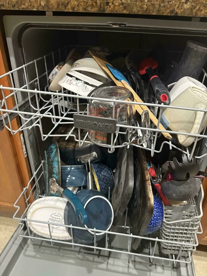 A poorly loaded Frigidaire dishwasher with mismatched dishes, capturing the sheer audacity of messy chores.