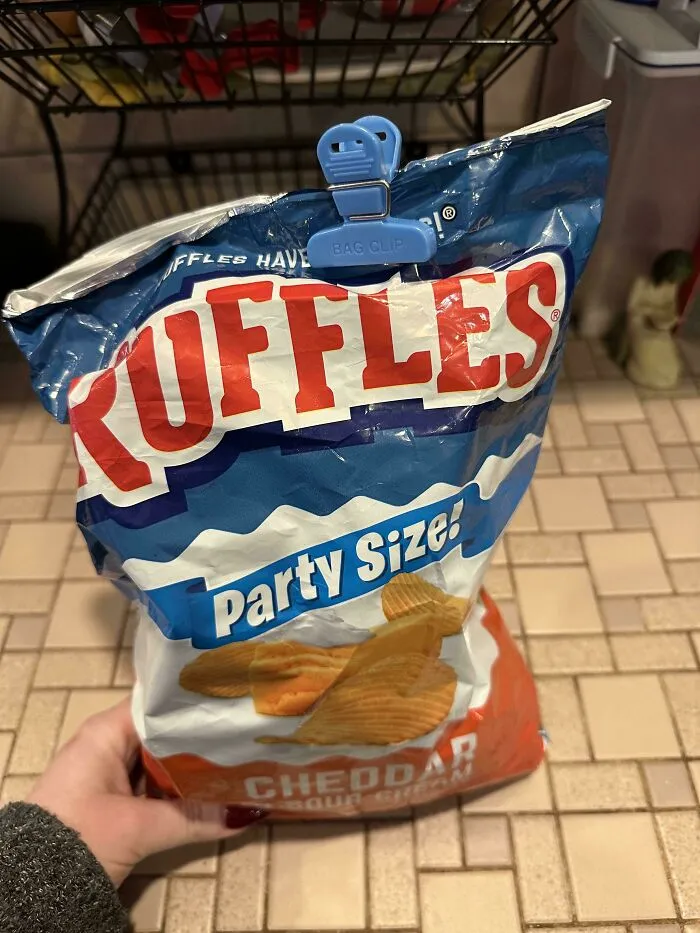 A bag of Ruffles chips sealed at the top with a clip, showing the audacity of opening it from the bottom.