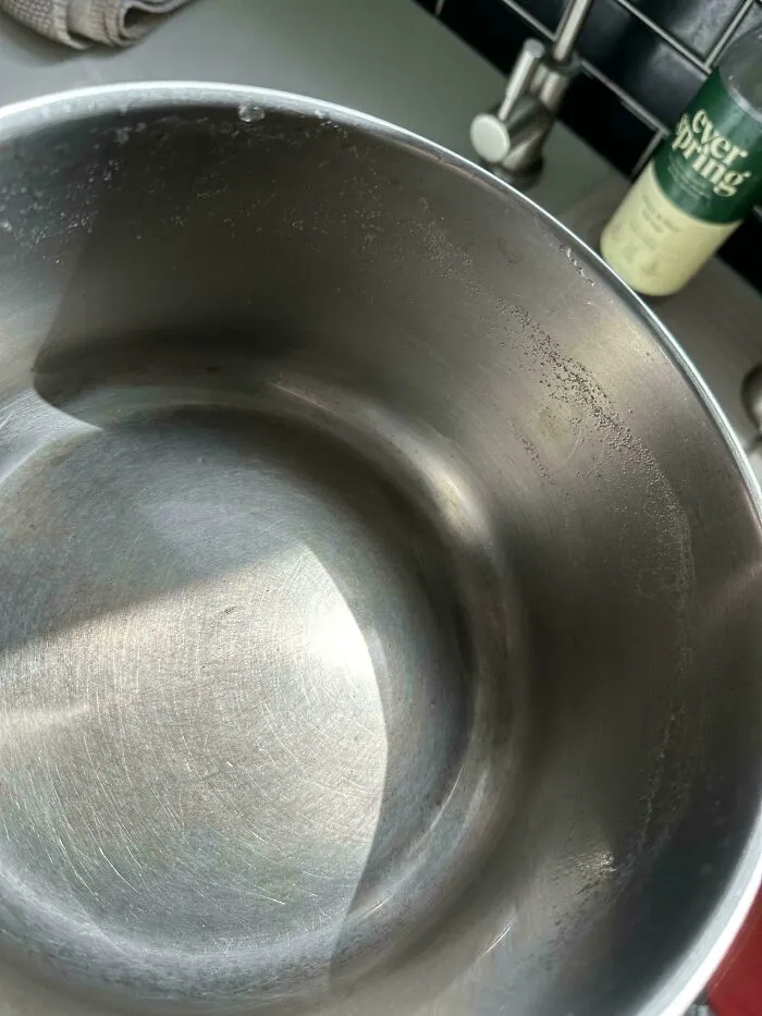 Dirty stainless steel pot with food residue highlighting the sheer audacity of some men in shared kitchens