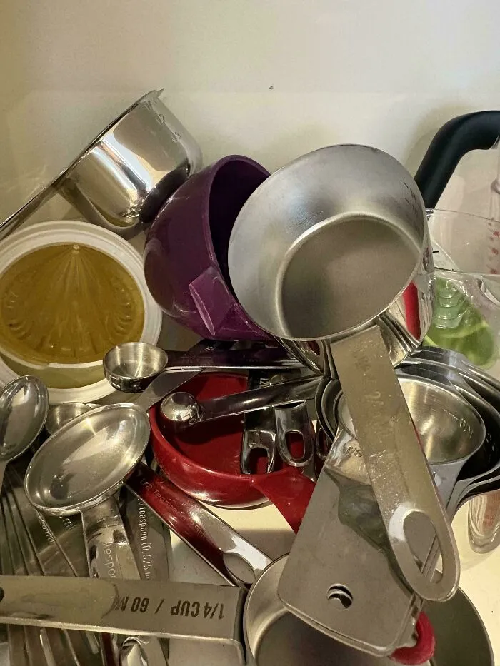 Messy pile of measuring cups and spoons shoved in a drawer, showing lack of organization
