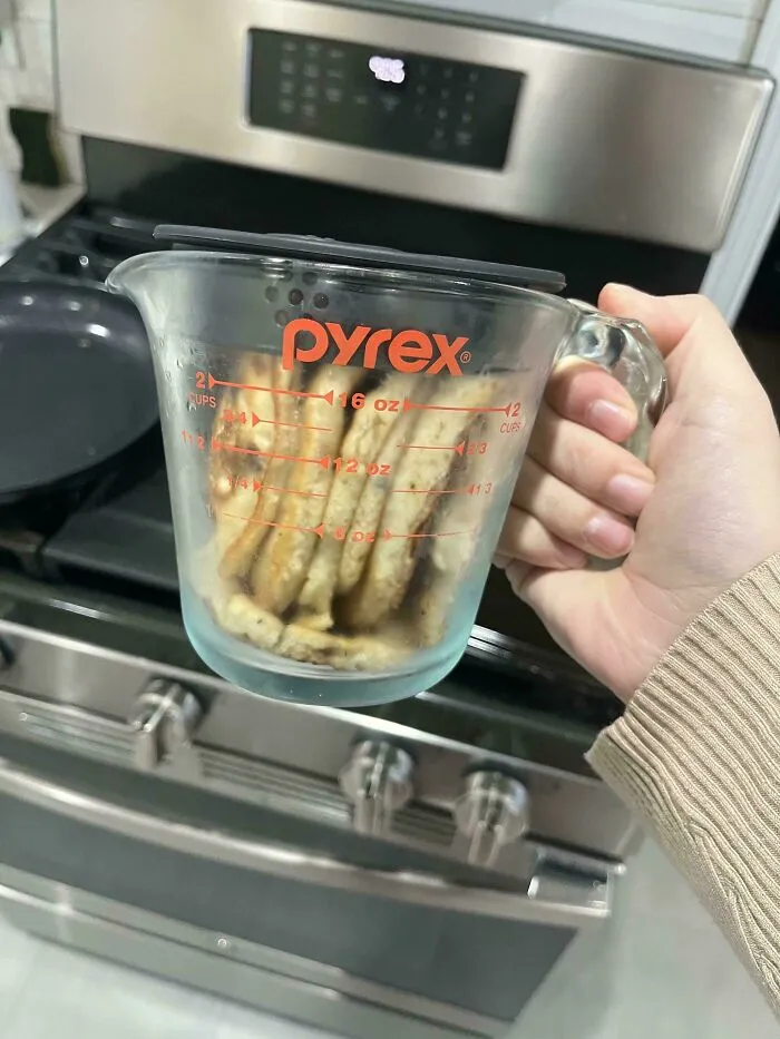 Slices of French toast stuffed vertically inside a Pyrex measuring cup with a lid