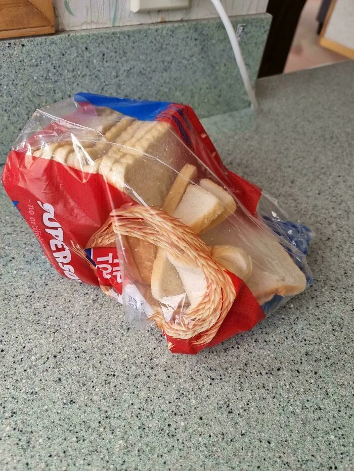 Loaf of bread sliced horizontally and messily inside its packaging on a kitchen counter