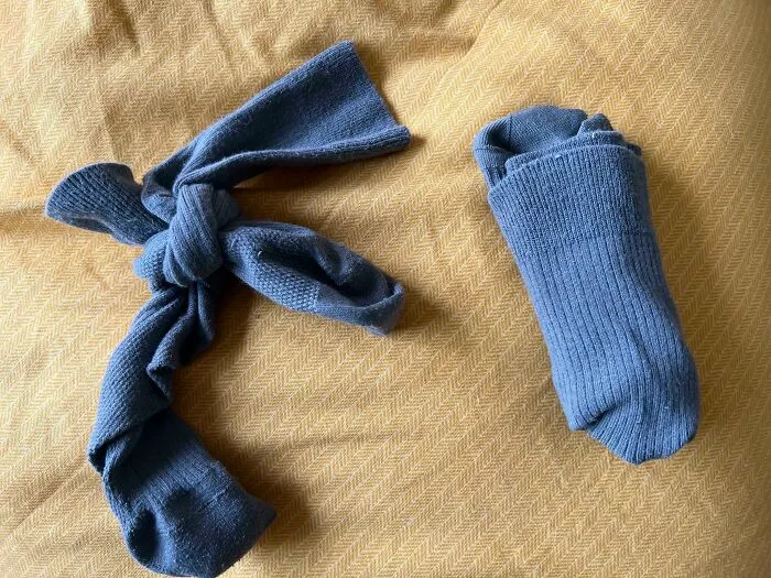 One sock tied in a knot and the other folded properly on a yellow surface