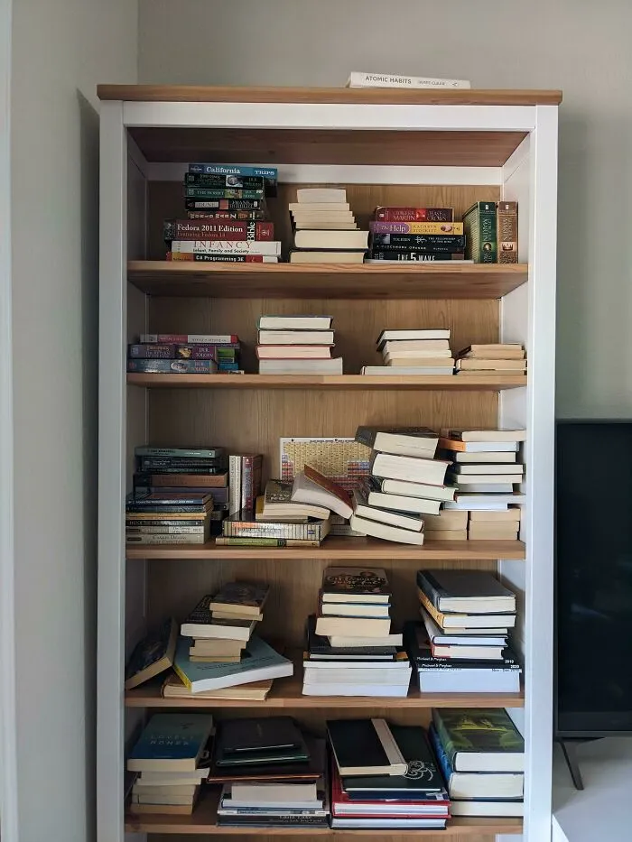 Unorganized bookshelf reflecting the chaotic energy and audacity some men bring.